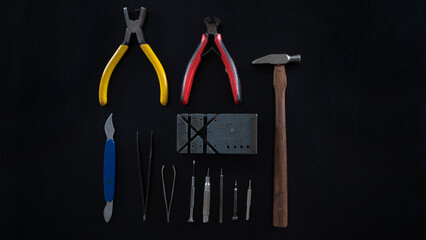 Several watch repair tools, isolated on black background, lay down on flat surface, top view