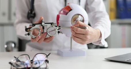 Ophthalmologist shows glasses for fitting optics and mockup of human eye