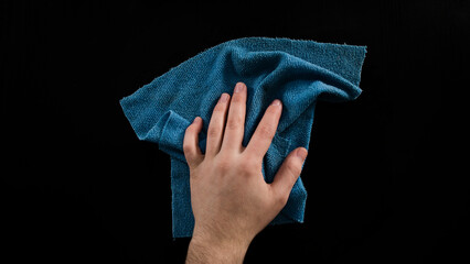 Cleaning table with blue cleaning cloth, male hand clean desk, isolated on black background, top view