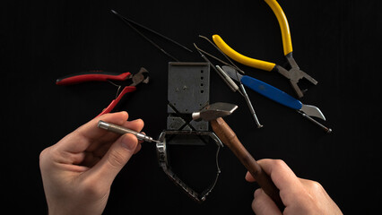 Repairing watch with tools, isolated on black background, male watchmaker hand, lay down, top view