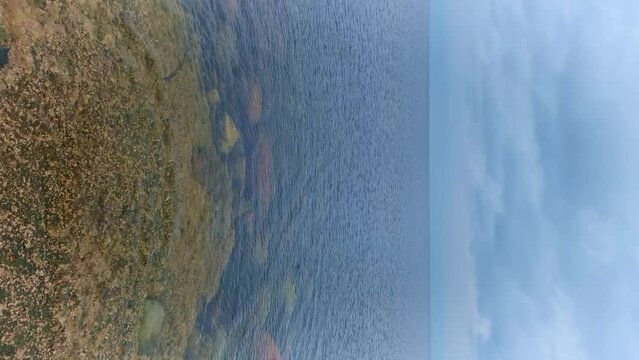 The stones lie near the coast of the Baltic Sea through the clear sea water. Clouds over the horizon during the day in spring. A small wind drives small frequent waves. Latvia