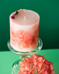 Handmade candles of a unique design, with different flowers, dry leaves on a light background. Candles made from organic wax, paraffin wax. Relaxation atmosphere. Luxurious lifestyle.