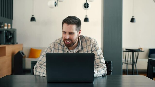 A young IT guy works at a computer and rejoices, he won