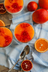 Panna cotta with jelly and red orange slices in glass bowls. Jelly creamy dessert on the table with citrus fruits.