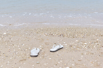 An old pair of white shoes on the beach by the sea