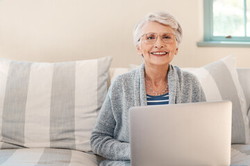 By far the easiest way to stay current. Shot of a senior woman using a laptop on the sofa at home.