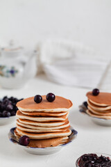 Homemade classic american pancakes with black currant on a light table. Sweet pancakes with berries.