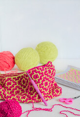 Creating a knitted bag with a bright ethnic geometric pattern. Pink yellow crocheted texture....