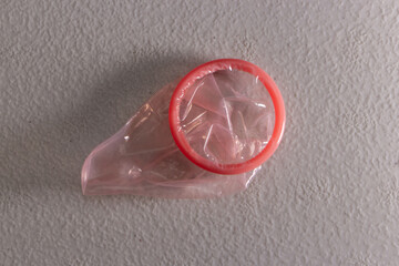 Conceptual image of unused pink color condom on the white table. Reducing the probability of...