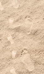 Fototapeta na wymiar Human footprints on dry sand in sunny summer day on a beach