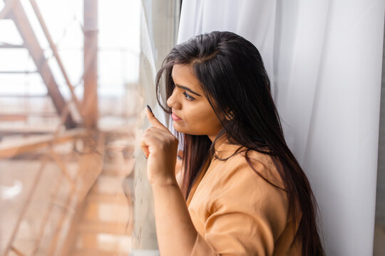 Young Indian woman looking out the window wistfully
