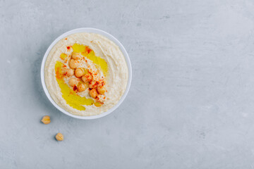 Fototapeta na wymiar Hummus with olive oil and paprika in a bowl on a gray concrete background