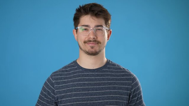 Portrait of smiling happy young hipstrman 20s isolated on plain blue background with copy space in studio