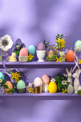 Obraz na płótnie Canvas Greeting card happy easter. Colored eggs easter decoration and spring flowers on small violet shelfs.
