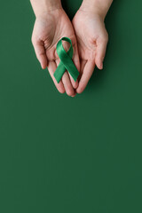 World bipolar day. Adult hands holding green ribbon. Mental health awareness day, Depression,...