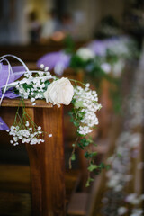 Close up church interior with white rose flower decorations on church seat armrest on wedding day