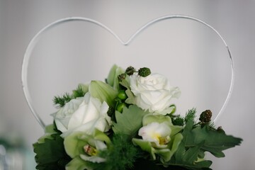 Heart-shaped wedding decoration support one jar with roses and ivy in a green context. Green wedding concept
