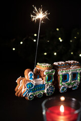Christmas gingerbread train with the sparklers in it. On the black background with the red candle