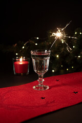 Festive beverage with the sparkler in it on a black background. Christmas decorations