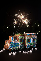 Christmas gingerbread train with the sparklers in it. On a black background with mini marshmallows