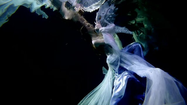 fantastic underwater shot with beautiful lady and dragon inside depth of magical ocean