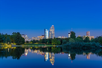 Fototapeta na wymiar Blue Hour With Enlightened Towers at La Defense District With Reflections on Lake