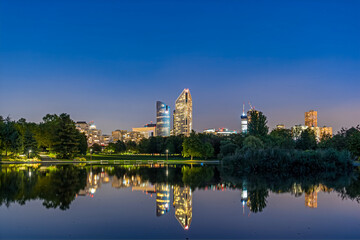 Fototapeta na wymiar Beautiful Scene of La Defense District at Dusk With Lake Lights Reflections and Trees