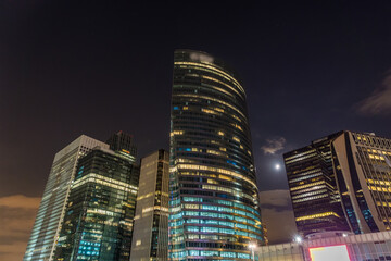 Obraz premium The Moon at Night Making Her Way Between Towers of La Defense Business District