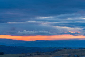 Colorful Rain Across Clouds During Sunset Over Hills Stormy Sky