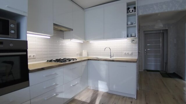 interior of cozy small kitchen with wooden floor, white cabinets and solid wood worktop.