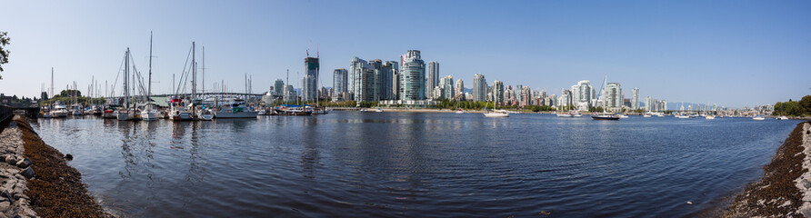 Fototapeta na wymiar Vancouver city skyline reflected in the water. Tall office buildings mirrored. Busy city life viewed from afar. Tranquil water. Blue skies. 
