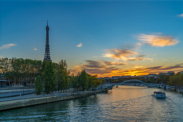 Fototapeta na wymiar Tourists on Boat Cruise at Golden Hour in Paris With Orange Sky and Eiffel Tower