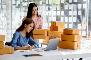 Portrait of Starting small businesses SME owners, two Asian woman check online orders Selling products working with boxs freelance work at home office, sme business online small medium enterprise