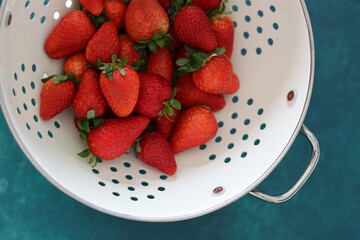 Juicy organic strawberry in white colander close up photo. 