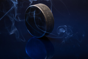 Closeup of a black ice hockey puck againsta blue background.