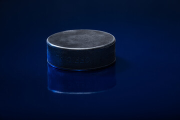 Closeup of a black ice hockey puck againsta blue background.
