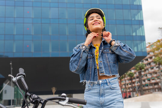 Happy ethnic woman fastening helmet before riding bicycle