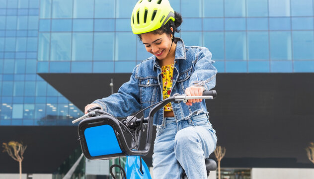 Smiling ethnic woman in helmet riding bicycle on city