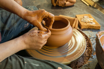 pottery, workshop, ceramics art concept - closeup on male hands sculpt new utensil with a tools and water, man's fingers work with potter wheel and raw fireclay, front close view - Powered by Adobe