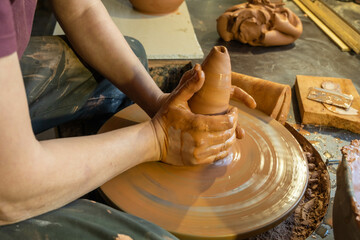 Men hands make earthenware cup working on pottery wheel at workshop. Top view.
