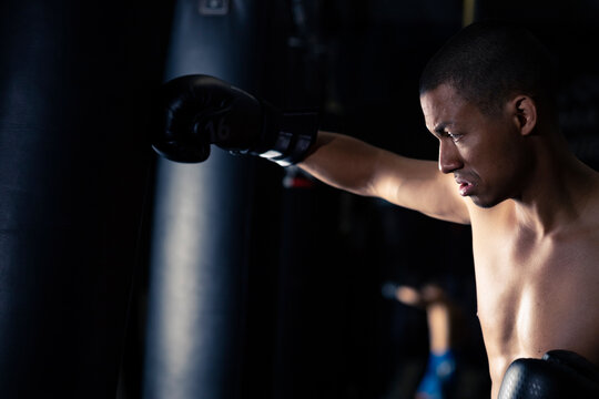 Shirtless Hispanic sportsman boxing in gym