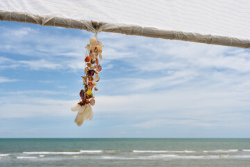 Seashell souvenir hanging decoration on wooden gazebo with tropical beach