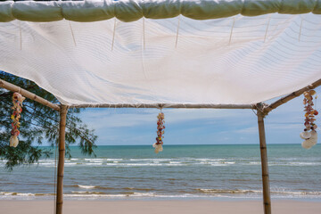 Seashell souvenir hanging decoration on wooden gazebo with tropical beach