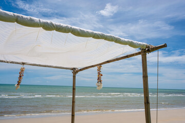 Seashell souvenir hanging decoration on wooden gazebo with tropical beach