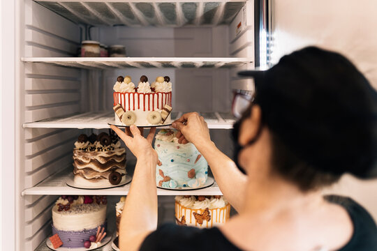 Crop baker putting cake in fridge
