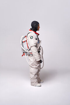 Serious ethnic astronaut in spacesuit and headset in studio