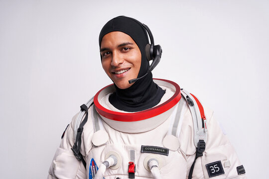 Smiling ethnic astronaut in spacesuit with headset for cosmos flight