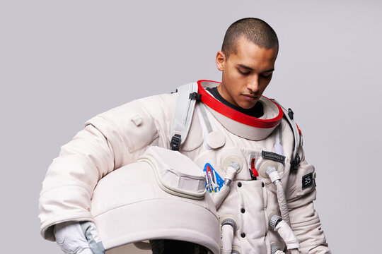 Astronaut taking off helmet of spacesuit in studio