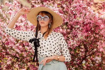 Outdoor lifestyle portrait of elegant fashionable woman wearing trendy straw hat, round blue...