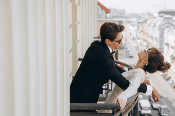 Beautiful and sexy bride and groom in a luxury hotel standing on the balcony overlooking the city....